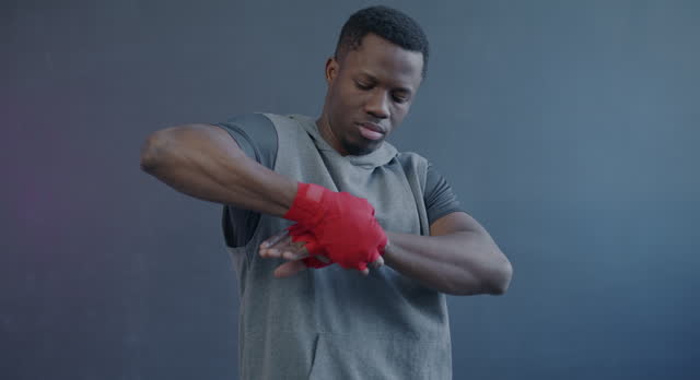 Portrait of African American boxer wrapping hands preparing for fight standding against purple color background