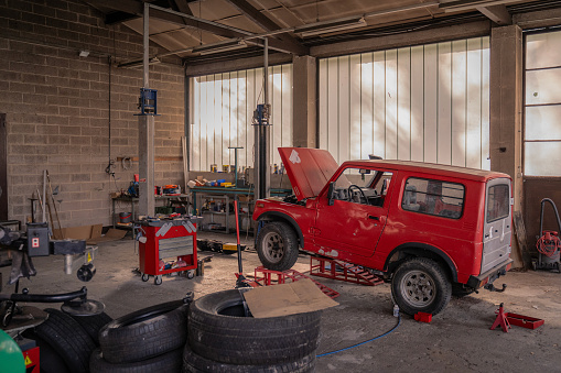 Off road vehicle in repair shop with hood open and elevated