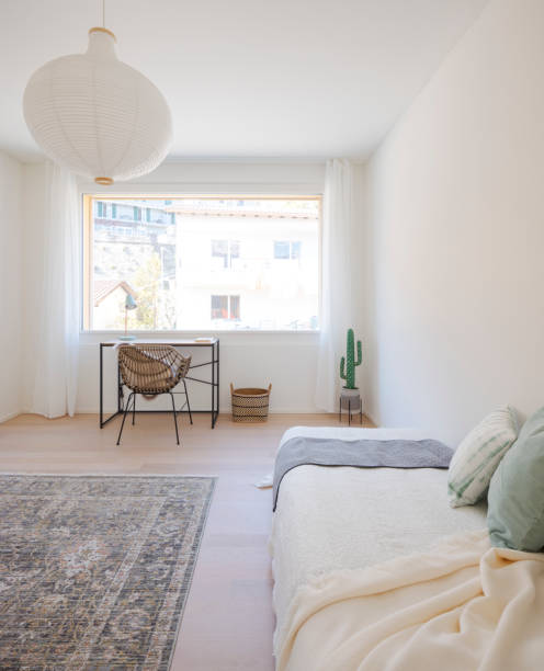 istock Front view of a small study with a small desk and an armchair. There is also a single bed with pillows and blankets. 2148253333