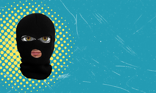 Contemporary art collage. Face in black balaclava isolated on a blue background. Concept of cyber security, fraud, or banditry.