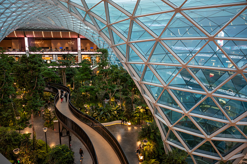 Doha, Qatar - April 09, 2024: Massive glass dome and elevated walkway above indoor garden at the Orchard at Doha's Hamad International Airport