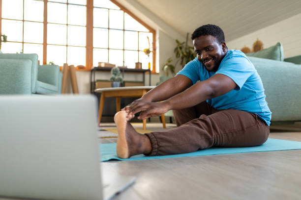 istock Young man using a laptop for exercising purposes at home 2148255174