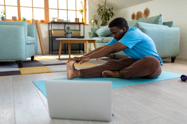 istock Young man using a laptop for exercising purposes at home 2148255175