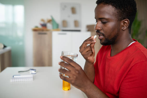 istock Young man taking medicine at home 2148255441