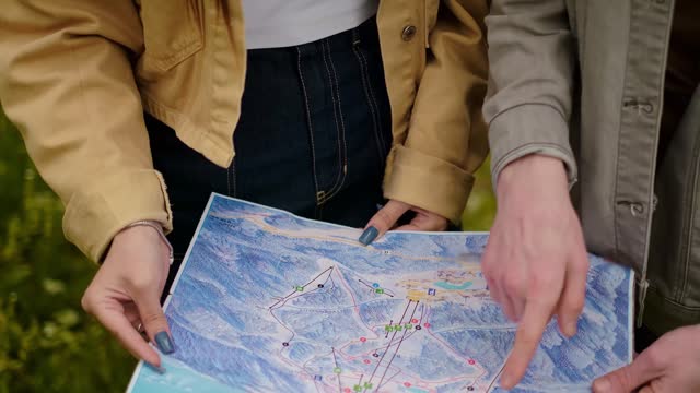 Young couple with a map, forest travelers. Finding their way, navigation tools, maps, and navigation apps, pointing the direction.