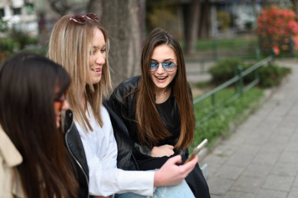 Smiling Female Friends Enjoying A Day Outside While Exploring Social Media
