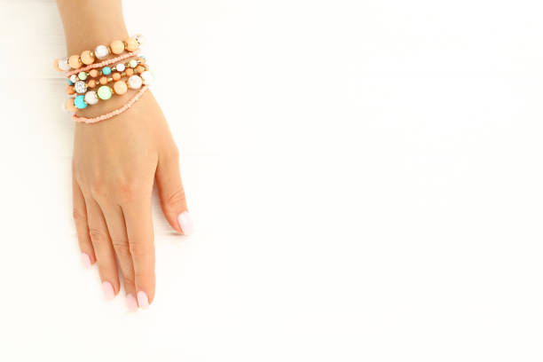 Female hand with bracelets on white wooden background