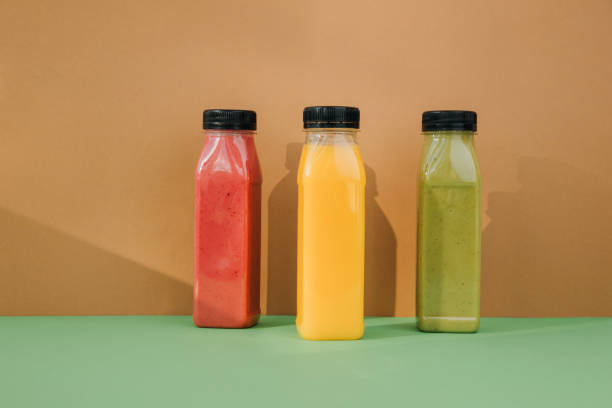 istock Fruit and vegetable smoothies in transparent plastic bottles. Red, green, orange smoothies on a brown-green background 2148258442