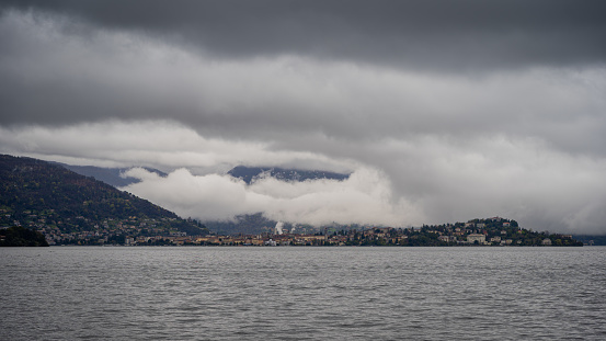 panorama of lake Maggiore on a rainy day with heavy low clouds covering part of the coast - travel and vacation concept