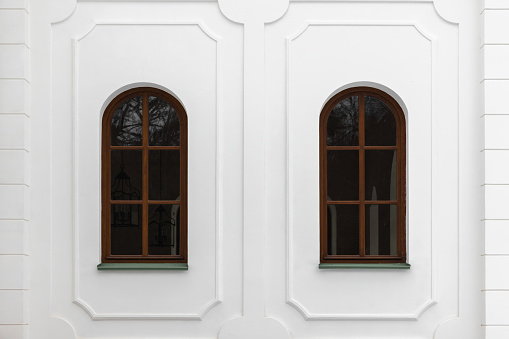 Classical windows with arches and decorative elements in white stone wall. Background photo texture