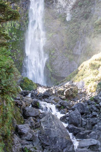 istock Sunlit waterfall cascades through lush NZ foliage, a serene Arthur's Pass gem 2148261575