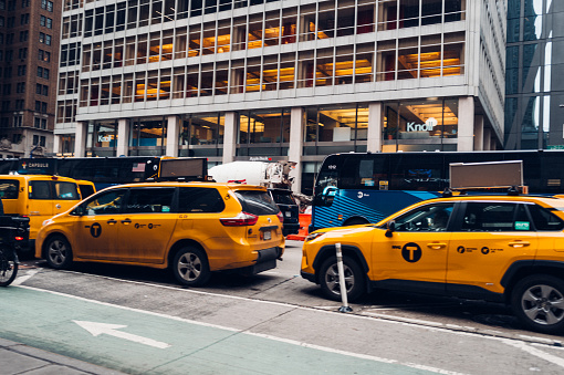 New York, United States of America - February 23, 2024: The image captures the iconic yellow cabs amidst Manhattan's vibrant scene on a busy street corner. Skyscrapers loom over lively streets, offering views of famous landmarks and embodying the lively essence of New York City.