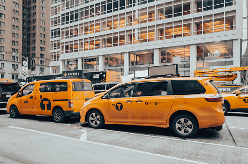 New York, United States of America - February 23, 2024: The image captures the iconic yellow cabs amidst Manhattan's vibrant scene on a busy street corner. Skyscrapers loom over lively streets, offering views of famous landmarks and embodying the lively essence of New York City.