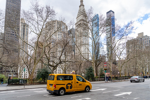 Manhattan, New York, USA - March, 2024.  Street photography in New York City with a yellow cab in front of Madison Square Park on a bright spring day.  It is near the Flat Iron building.