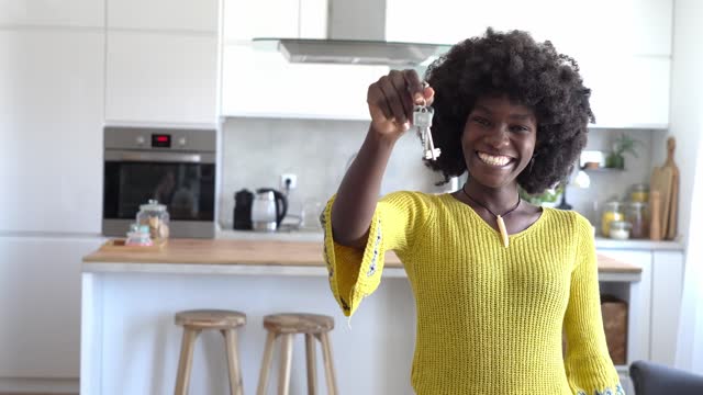 An African-American woman is holding keys of her new home