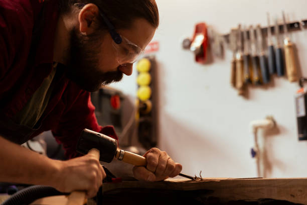 istock Artist makes wood sculptures, engraving lumber with tools, using protective gear 2148266244