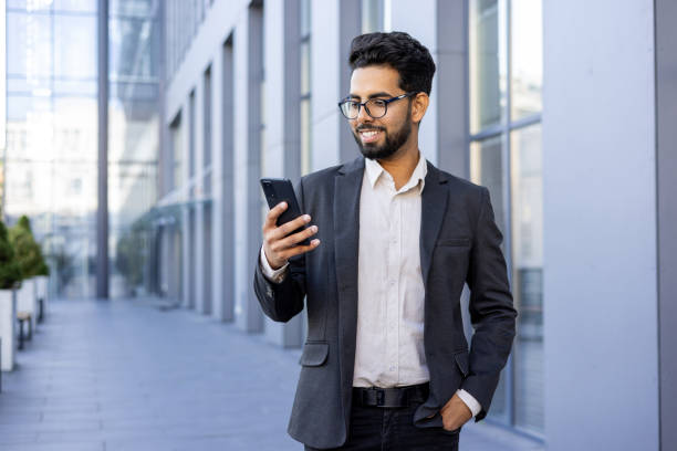 istock Smiling young Indian businessman using smartphone in urban setting 2148266842