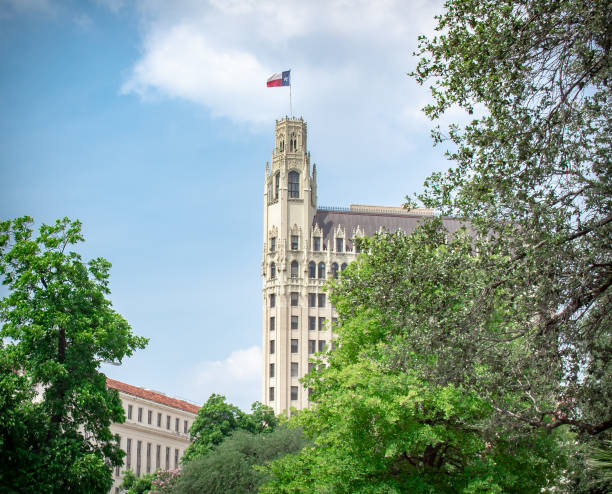 Historical building with the  Texas flag surrounded by buildings surrounded by trees