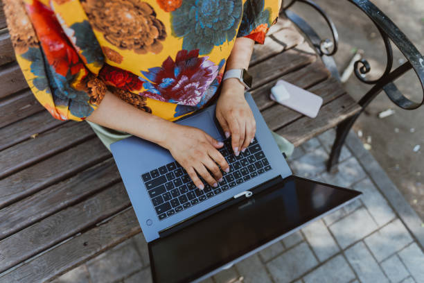 istock Female hands working on her laptop while sitting on park 2148267320