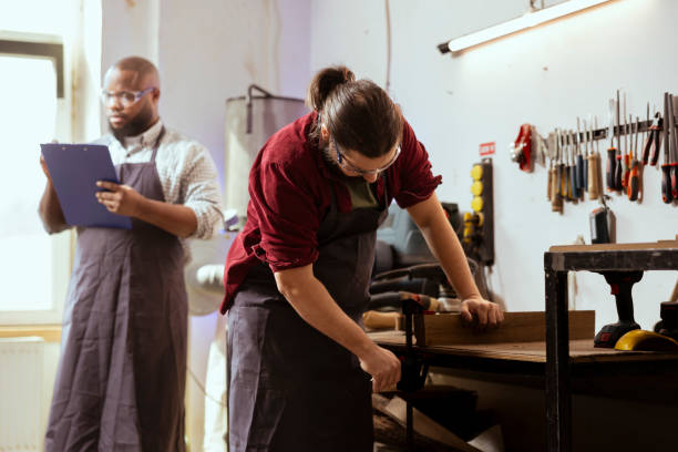 istock Woodworker and coworker using bench vise to hold lumber block 2148267583