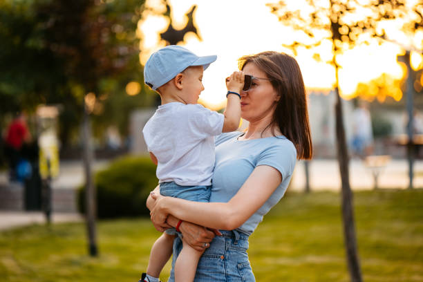 Beautiful young mother holding her son in the park.