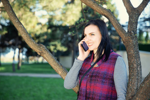 Woman having fun talking on the phone while standing in the park