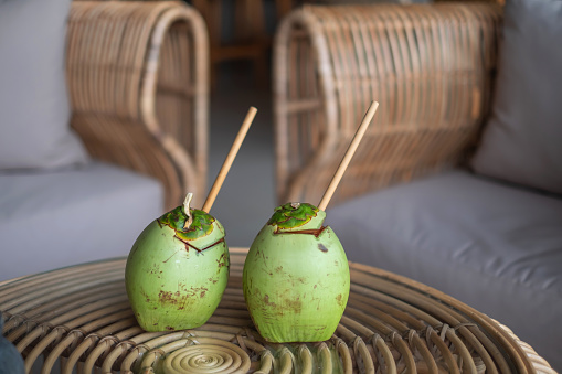 Close up shot of two young green coconut above a coffee table in a villa, served as a welcome drink.