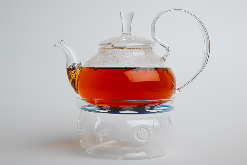 Transparent glass teapot with tea isolated on white background
