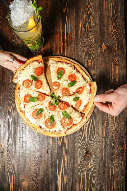istock Person Holding Pizza on Wooden Table 2148271032