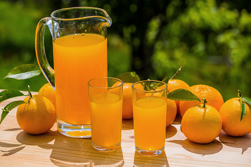 Orange juice and oranges on kitchen countertop, directly above, table top shot. Fresh fruit juice in glass bottle and drinking glass.