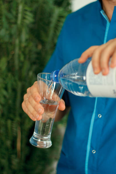 istock man pours water from a bottle into a glass 2148271939