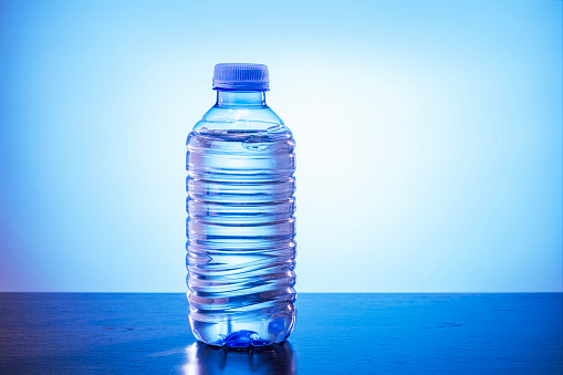 Bottle of water bottled in a container of recycled plastic on blue background. Drink water.