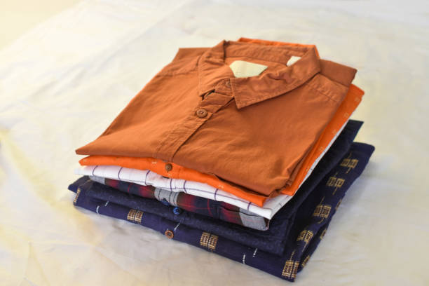Ironing, laundry, clothes, housekeeping and objects concept - close up of ironed and folded shirts on table at home.