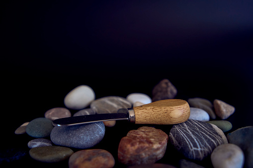 a fish and cheese knife with a wooden handle on a black background with sea pebbles
