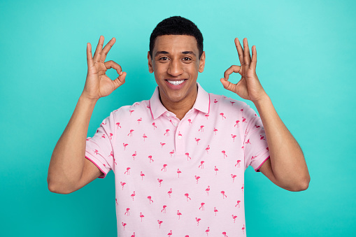 Photo of positive guy toothy smile arms arms fingers demonstrate empty space approval isolated on teal color background.