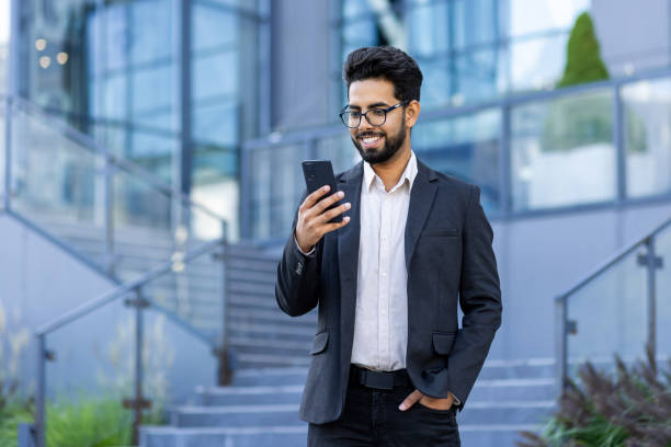 istock Smiling Indian businessman using smartphone outside modern office 2148274474