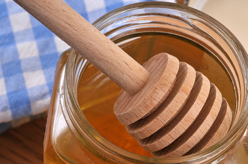 Wooden honey spoon in a honey pot closeup