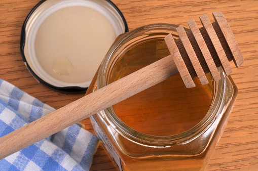 Wooden honey spoon placed on a pot of honey