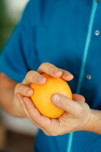 массажист держит в руках апельсин