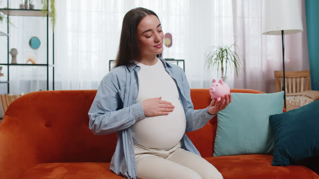 Pregnant woman inserting banknote money cash dollar in piggybank saving for baby's future needs