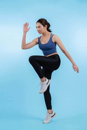 Side view young athletic asian woman on running posture in studio shot on isolated background. Pursuit of healthy fit body physique and cardio workout exercise lifestyle concept. Vigorous