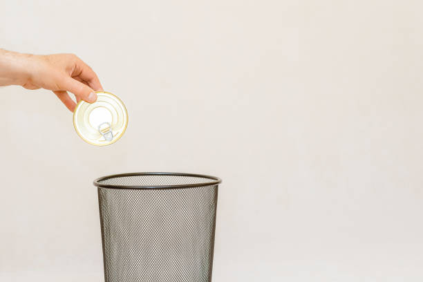 the closed metal carbonate can food conserve is thrown into the trash for disposal and recycling.white,gray background,selective focus,copy space. - 11262 foto e immagini stock