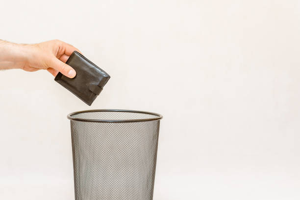 istock The black wallet is thrown into the trash,can for disposal and recycling.White,gray background,selective focus,copy space. 2148277270