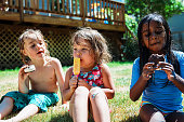 Multiracial group of friends eating ice cream outside on summer afternoon