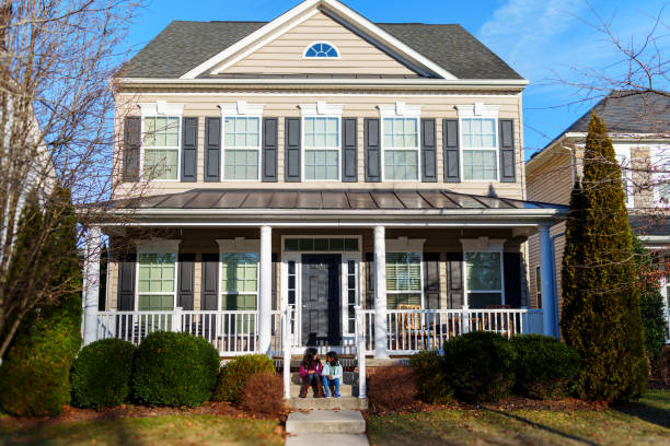 Two elementary age girls of Indian descent sit side by side on the steps to the front porch of their home and wait for the school bus to pick them up on a cool and sunny morning in Maryland.