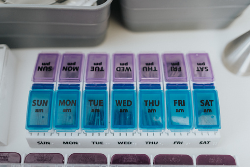 A purple and blue, weekly medicine binder filled with pills sits on the counter of a dentists office, ready for use.