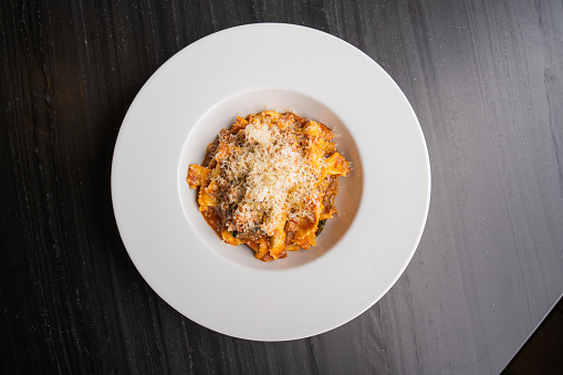 View of a gourmet Ticinese meal, bowl of pasta with meat sauce and parmesan cheese