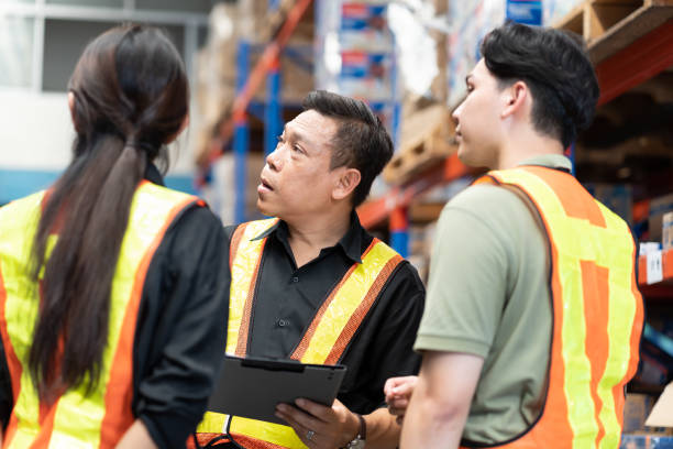 istock Male and female warehouse workers working and standing talking together at the storage warehouse. Group of warehouse workers discuss and training work in distribution branch 2148281915