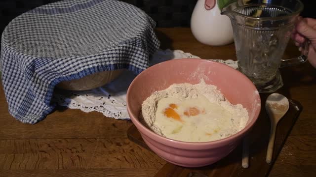 Pouring milk into a  vintage  bowl  with flour  and  eggs