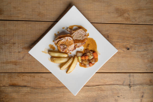 A plate of food with a red sauce drizzled over it. The plate is white and has a design on it